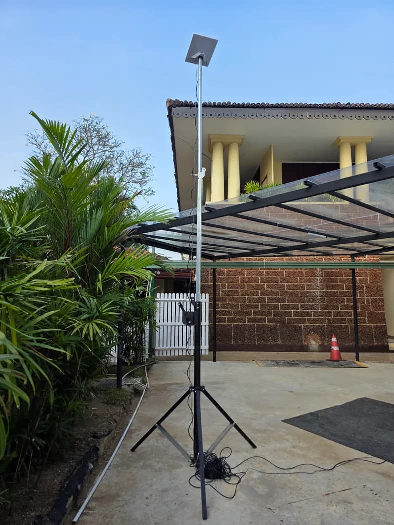 Starlink Mini on a raised tripod mast in a driveway, full setup view